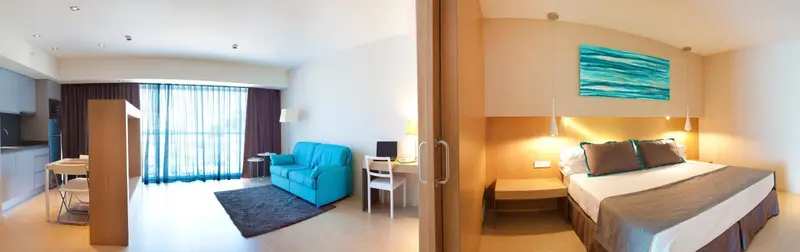 Espace de vie lumineux avec canapé bleu turquoise et chambre à coucher.