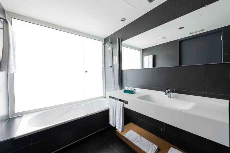 Une salle de bain moderne avec baignoire et vasque blanche.