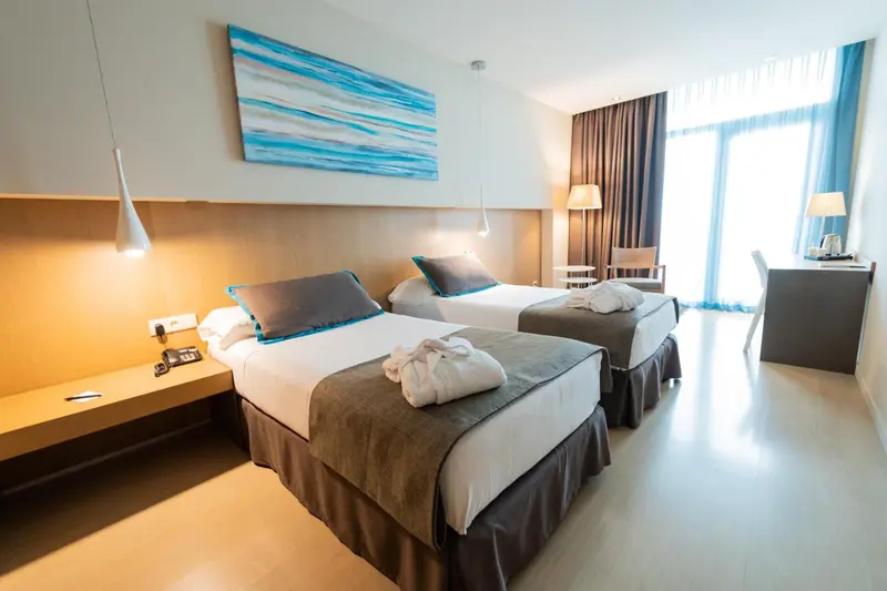 Chambre lumineuse avec deux lits simples et une décoration moderne.