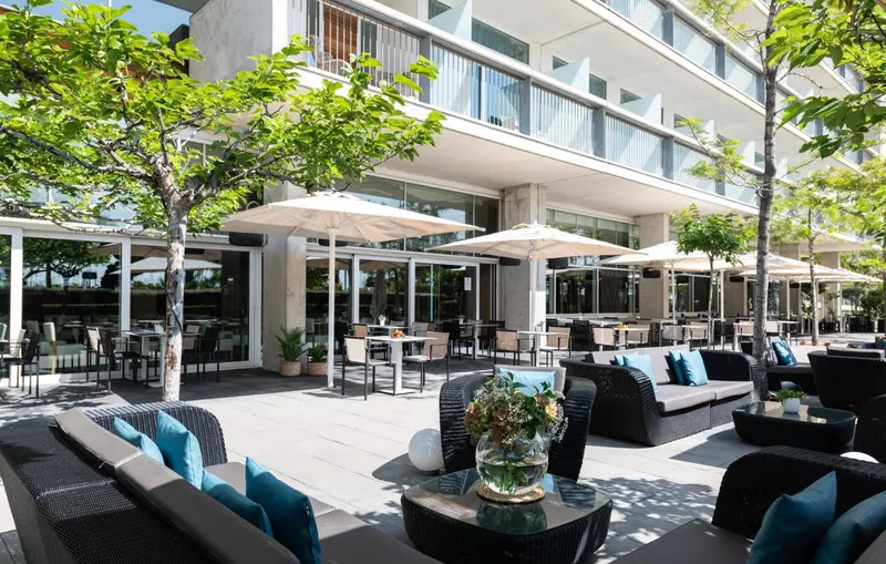 Terrasse ombragée avec mobilier de salon et tables de repas.