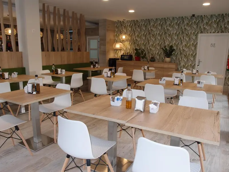 Une salle lumineuse avec des tables et des chaises blanches, prête pour le service.