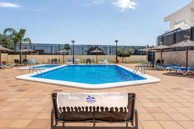 Une piscine rectangulaire avec des transats et des parasols.