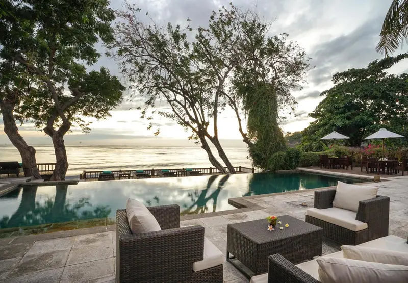 Terrasse avec mobilier de jardin et piscine à débordement donnant sur la mer.