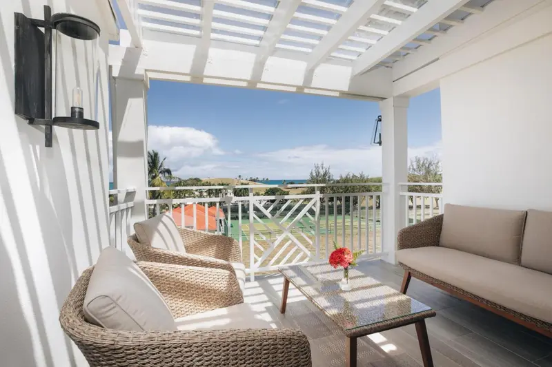 Espace de détente extérieur avec mobilier en rotin et vue sur la végétation.