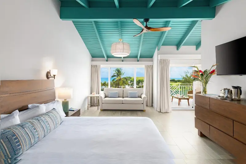 Une chambre lumineuse avec un grand lit et un canapé face à une vue sur la mer.