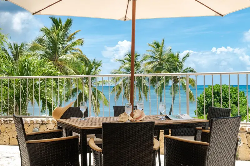 Une table est dressée sur une terrasse avec vue sur la mer et la végétation.