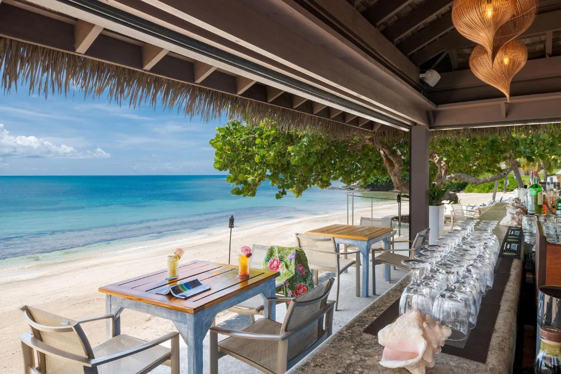 Une table est dressée sur une terrasse en bord de mer avec des cocktails colorés.