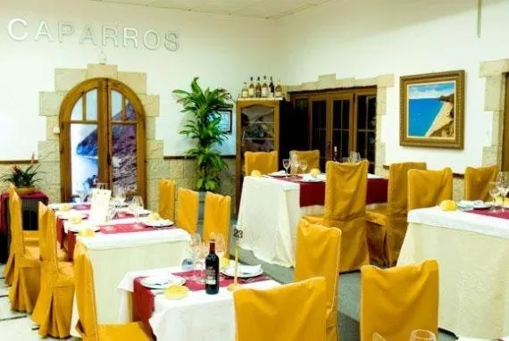 Une salle de restaurant lumineuse avec des tables dressées et des chaises recouvertes de tissu jaune.