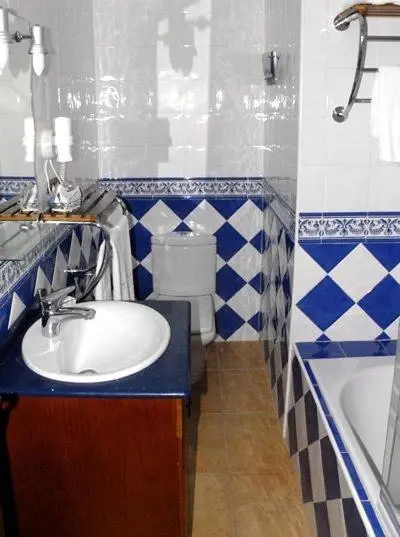 Une salle de bain carrelée avec lavabo, toilette et baignoire.