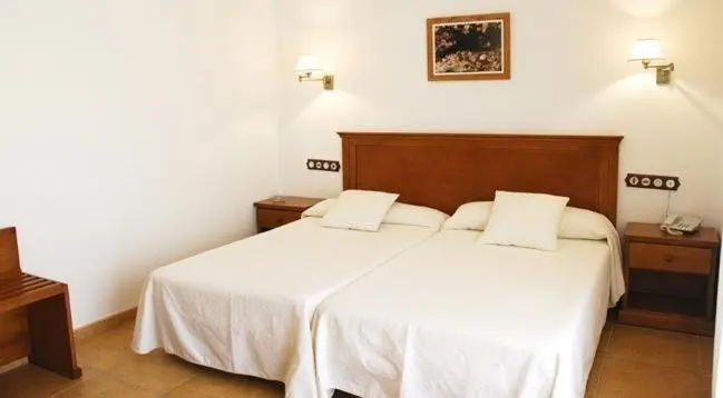 Une chambre lumineuse avec deux lits simples et des tables de chevet.