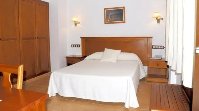 Une chambre lumineuse avec un lit double et des meubles en bois.