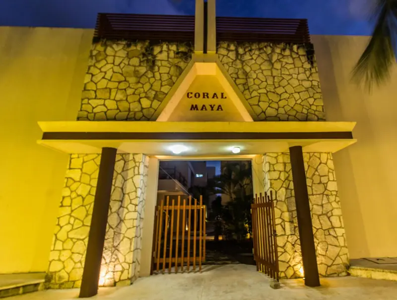 Entree illuminée d'un bâtiment en pierre avec une arche et un portail en bois.