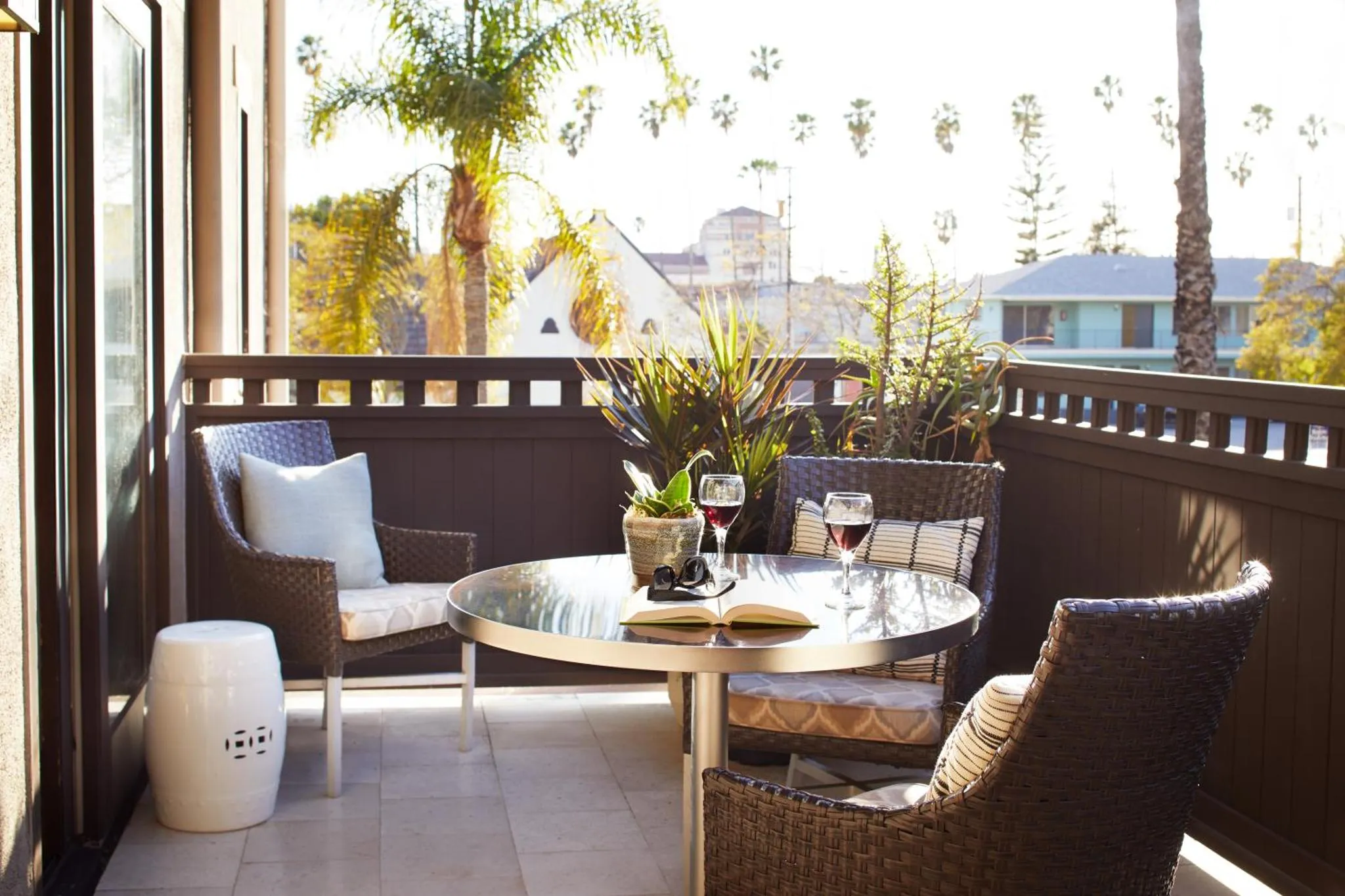 Une table ronde et des fauteuils en osier invitent à la détente sur une terrasse ensoleillée.