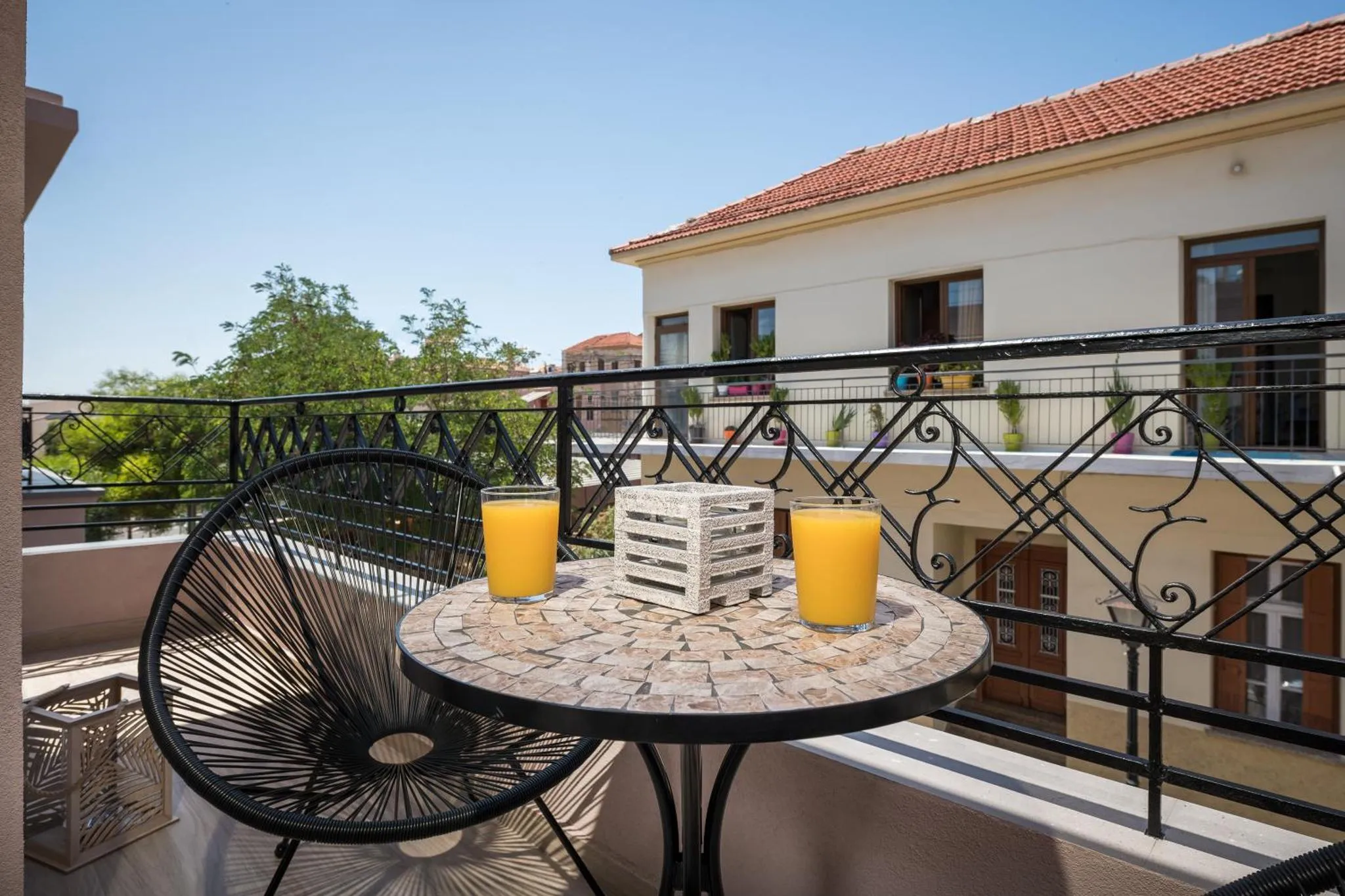 Une table ronde avec des verres de jus d'orange sur une terrasse ensoleillée.