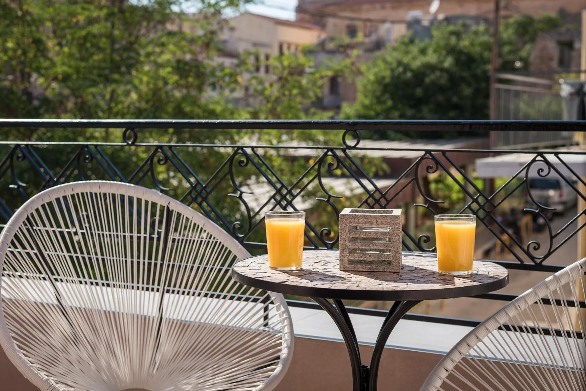 Une table ronde avec des verres de jus d'orange sur une terrasse ensoleillée.