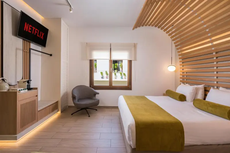 Une chambre lumineuse avec un grand lit et un fauteuil.