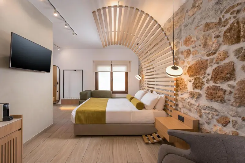 Une chambre lumineuse avec un lit double et un mur en pierre.