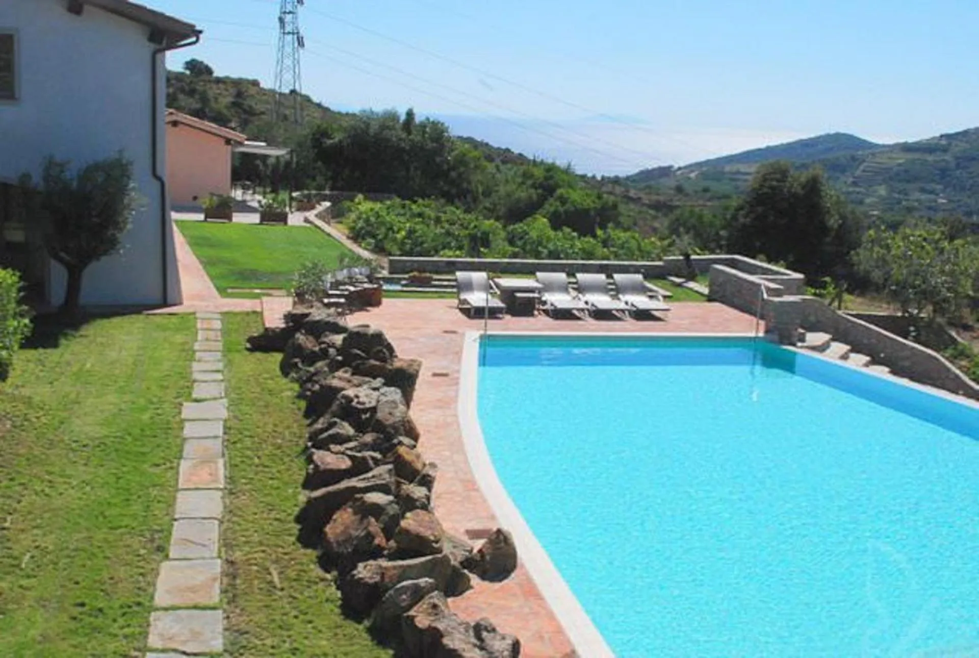 Une piscine rectangulaire bordée d'une terrasse ensoleillée avec des transats.