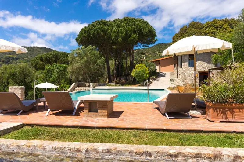 Transats et piscine ensoleillés avec vue sur la végétation et les collines.