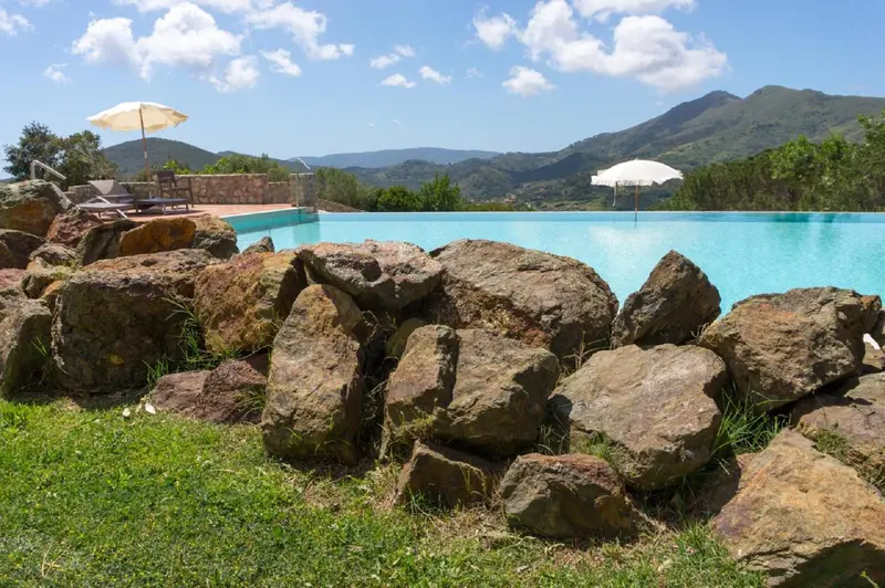 Une piscine à débordement avec un cadre rocheux et une vue sur les montagnes.