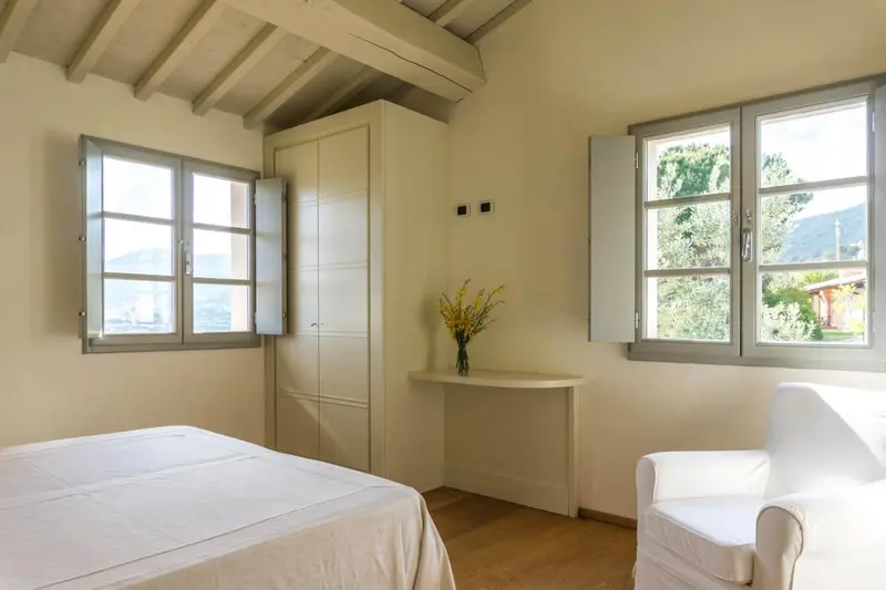Une chambre lumineuse avec un lit fait et un fauteuil.