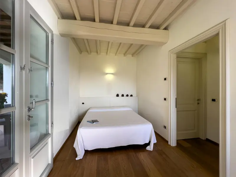 Une chambre lumineuse avec un lit recouvert de blanc et un parquet en bois.
