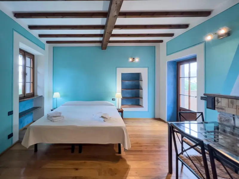 Une chambre lumineuse avec un lit blanc et des murs bleus.