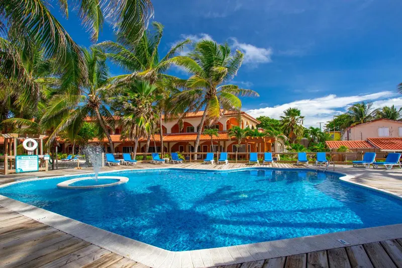 Une piscine turquoise bordée de transats dans un cadre tropical.