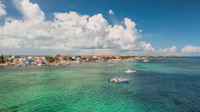 Vue aérienne d'une côte turquoise avec des bateaux et des bâtiments colorés.