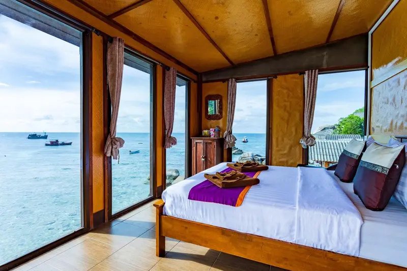 Chambre lumineuse avec un lit fait donnant sur la mer.