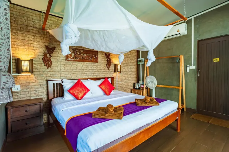 Une chambre avec un lit à baldaquin décoré de coussins rouges et d'une moustiquaire blanche.