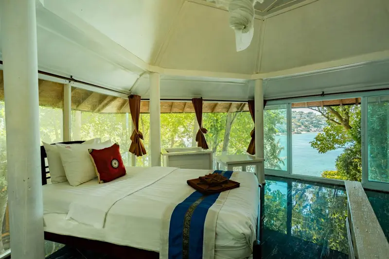 Une chambre lumineuse avec un grand lit donnant sur une vue sur la mer.