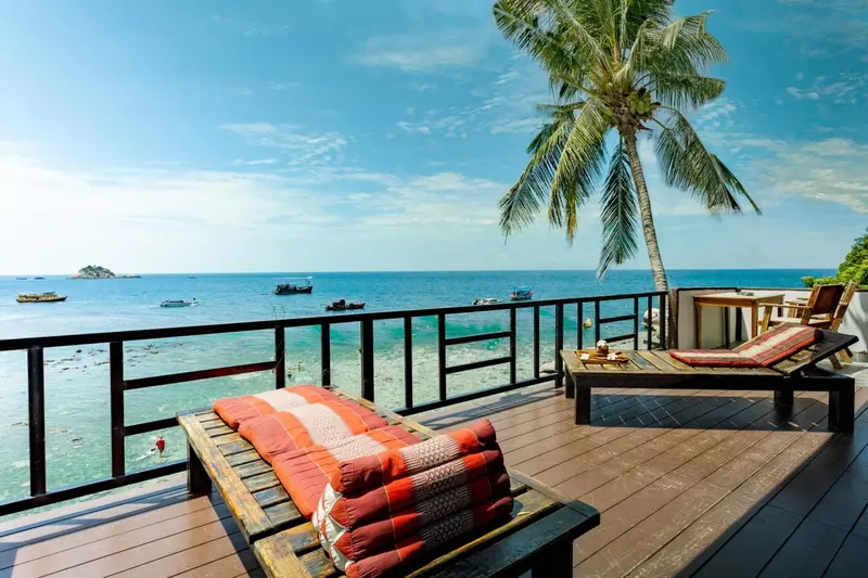 Terrasse en bois avec chaises longues donnant sur la mer et le ciel bleu.