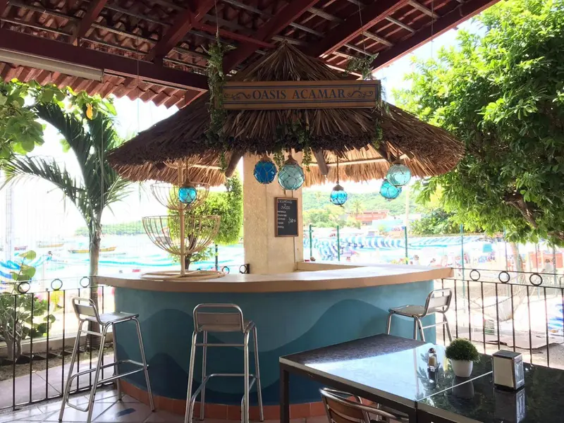 Un bar extérieur avec des tabourets et une table à proximité d'une piscine.