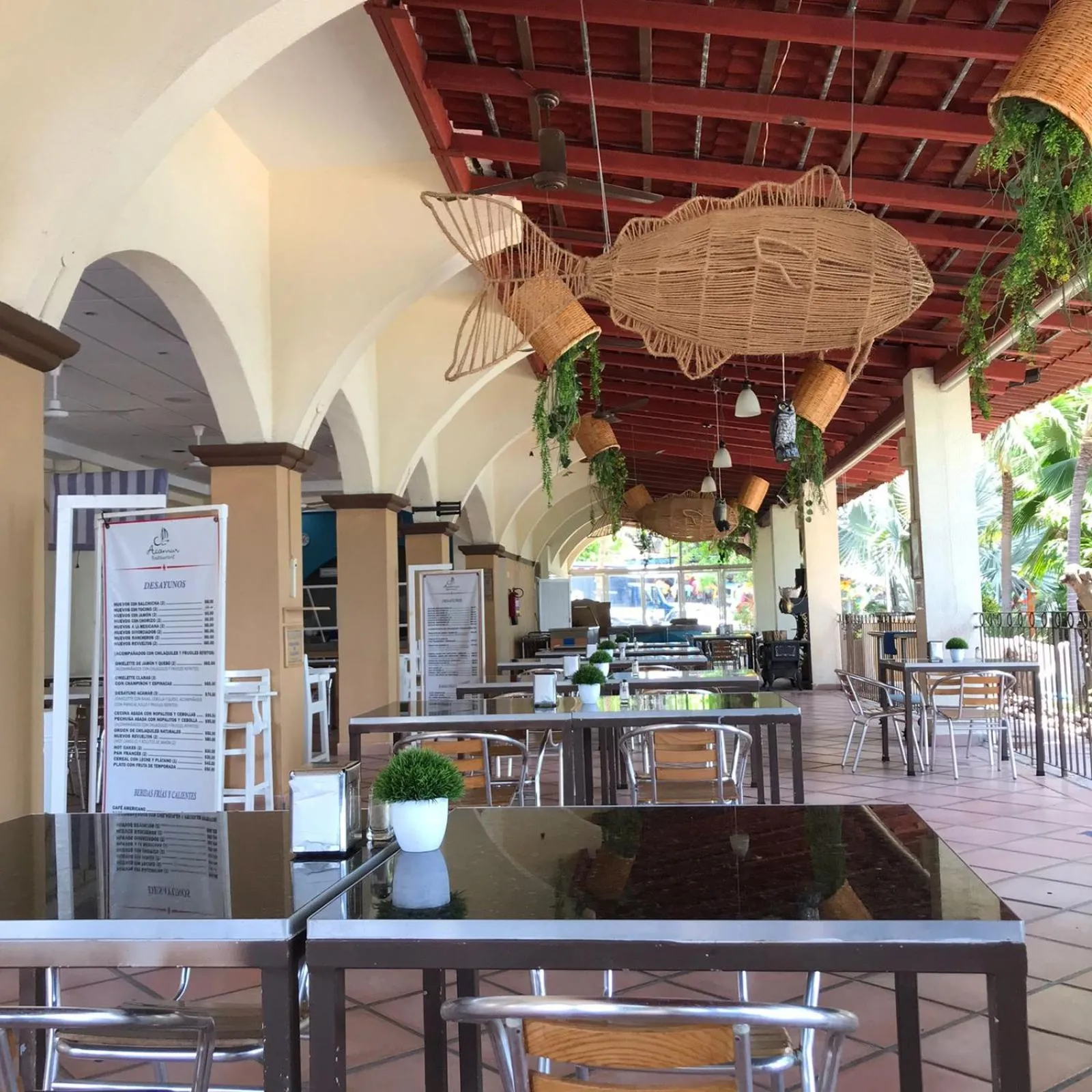 Une salle à manger extérieure ombragée avec des tables et des chaises.
