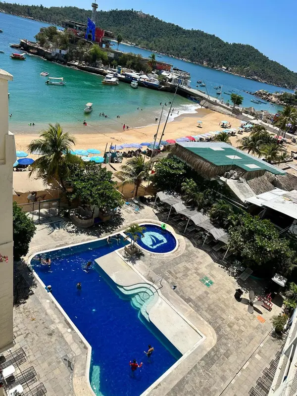 Vue aérienne d'une plage avec une piscine et des bateaux dans une baie.