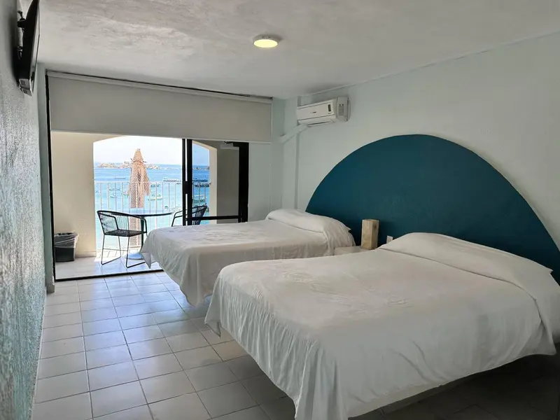 Chambre lumineuse avec deux lits simples et vue sur la mer.