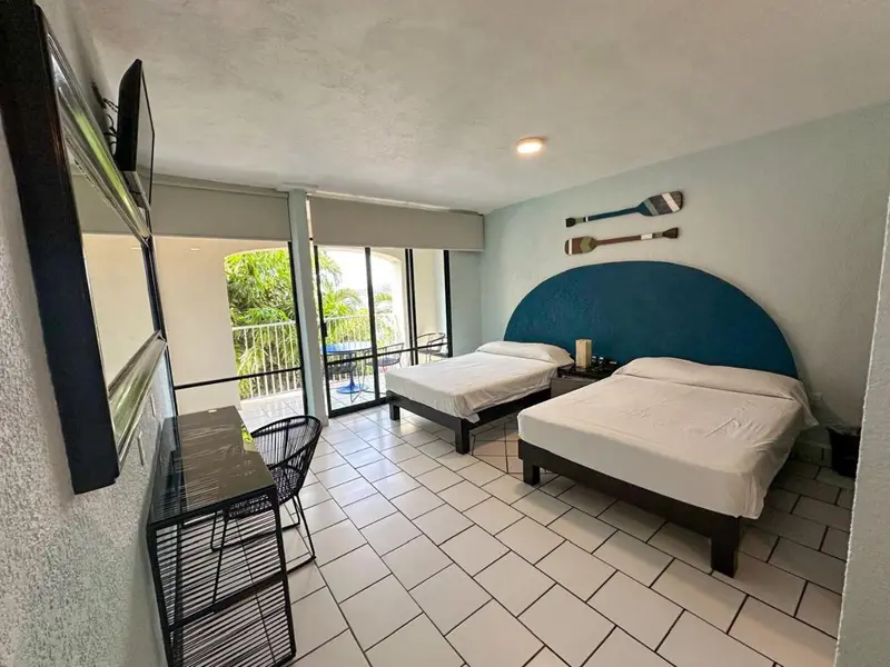 Une chambre lumineuse avec deux lits et un balcon.