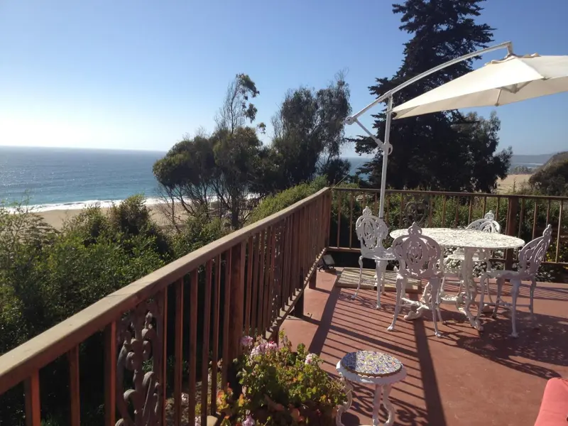 Terrasse en bois avec mobilier de jardin et vue sur la mer.