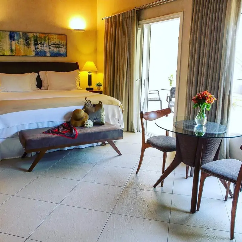 Une chambre lumineuse avec un grand lit et un coin repas.