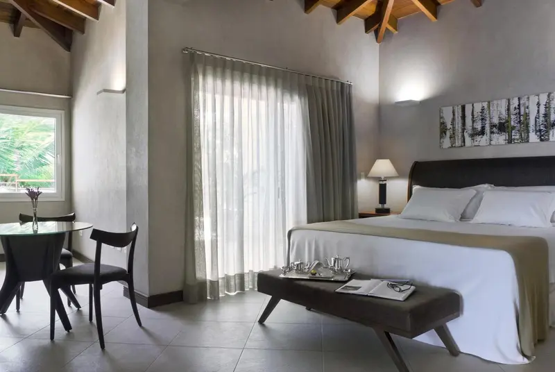 Une chambre lumineuse avec un lit fait et un coin repas.