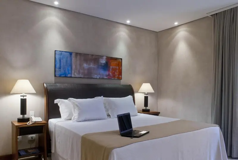 Une chambre lumineuse avec un grand lit et deux lampes de chevet.