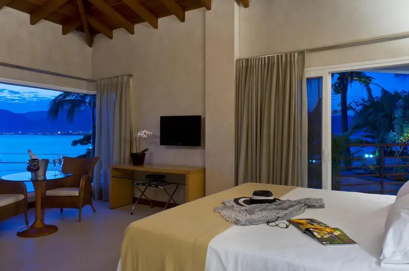 Une chambre lumineuse avec un lit et une table basse donnant sur une vue nocturne sur la mer.