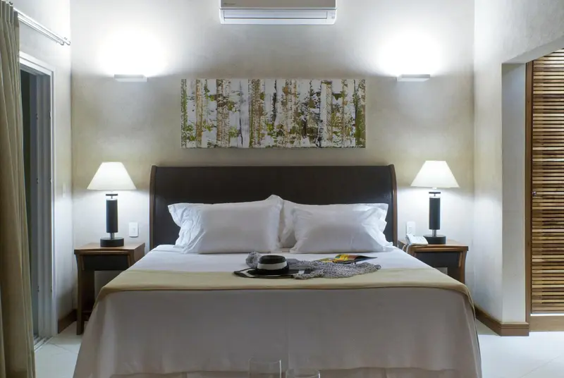 Un lit double blanc est dispose dans une chambre claire.