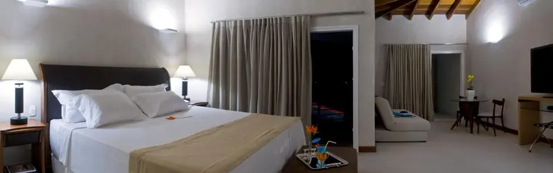 Une chambre lumineuse avec un grand lit et un coin salon.