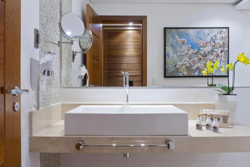 Un lavabo blanc moderne avec un grand miroir et des accessoires de salle de bain.