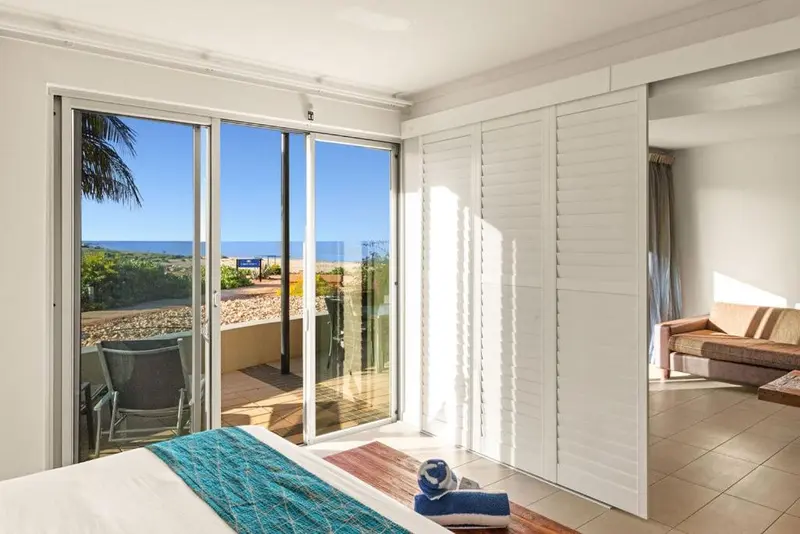 Une chambre lumineuse s'ouvre sur une terrasse avec vue sur la mer.