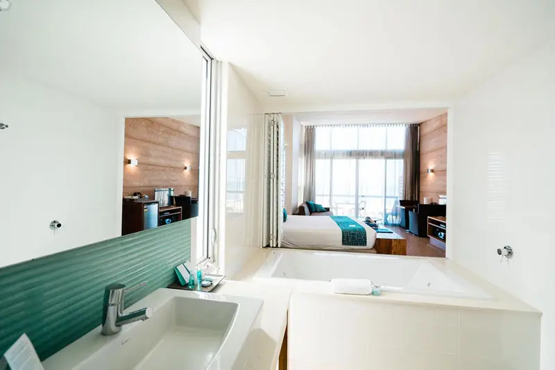 Une salle de bain lumineuse s'ouvre sur une chambre avec vue sur la mer.