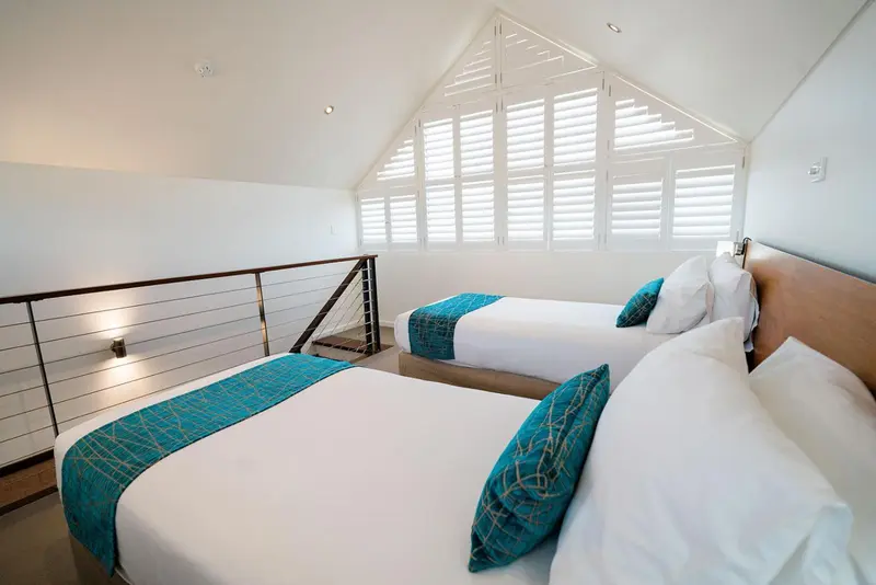 Chambre lumineuse avec deux lits simples et décoration turquoise.