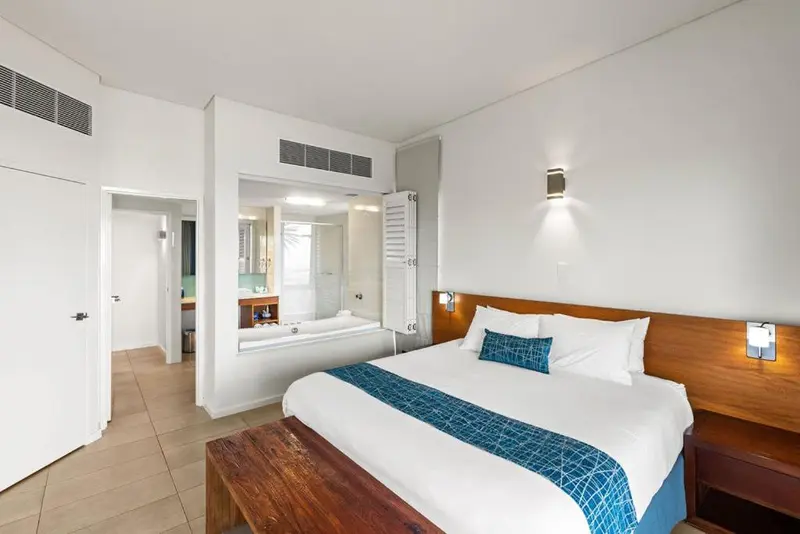 Une chambre lumineuse avec un grand lit et un espace baignoire.